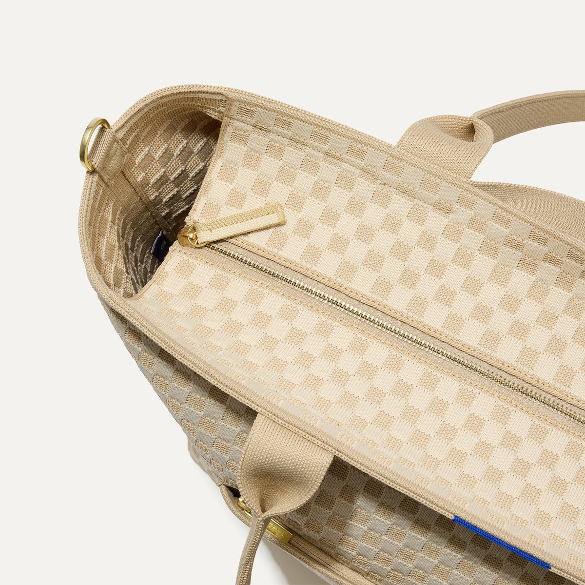 A close up of The Zip Travel Tote in Parchment Basketweave, focusing on the zip closure and handles.